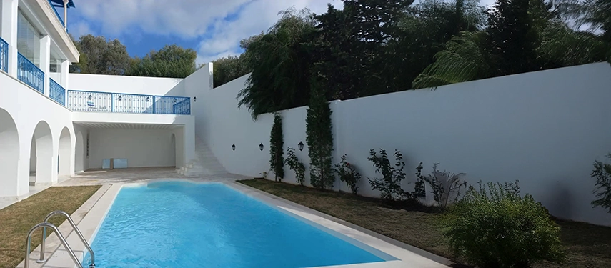 Serene outdoor pool area surrounded by whitewashed walls and lush greenery.