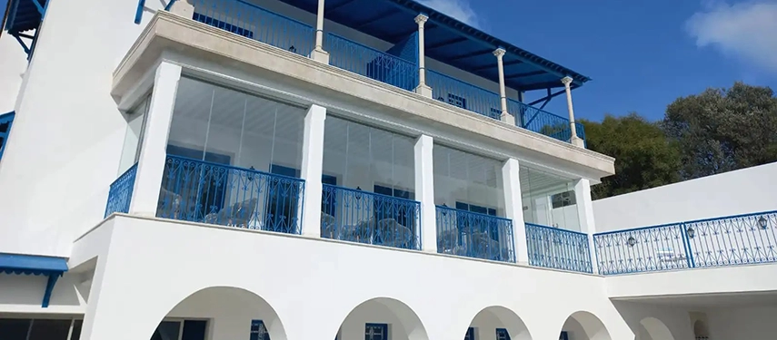 Hotel exterior with striking white arches, blue balconies, and glass-panelled terraces.