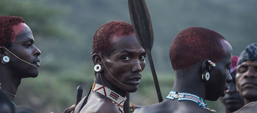 Close-up of Samburu warriors adorned with traditional jewellery and ochre-dyed hair, engaged in an intense cultural moment.