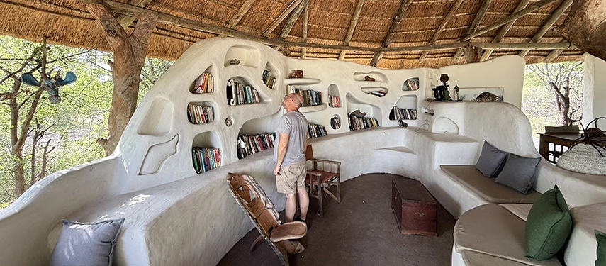 A guest browses books in Moela’s sculpted open-air lounge, a tranquil communal space designed for quiet moments between safari activities.