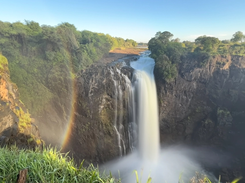 Victoria Falls plunges into the gorge below as mist rises and a rainbow forms, revealing one of Africa’s most powerful natural spectacles. 