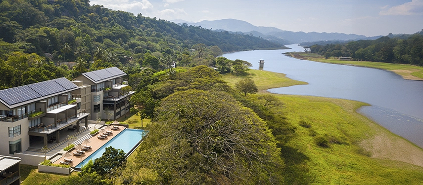 A drone view highlights Jetwing Kandy Gallery’s modern architecture and riverside pool set against rolling green hills.