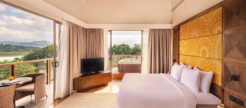 A spacious guest room at Jetwing Kandy Gallery opens to wide river views, warm natural light and a private outdoor jacuzzi on the balcony.