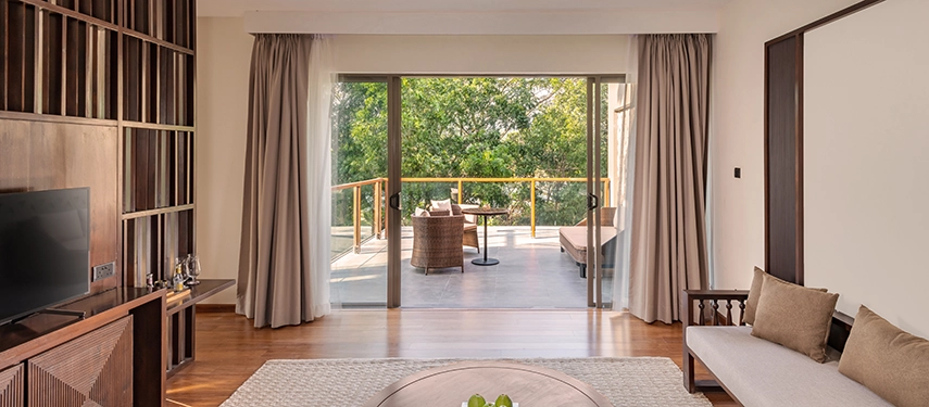 A serene living space at Jetwing Kandy Gallery flows out to a furnished terrace shaded by trees, creating a peaceful indoor-outdoor retreat.