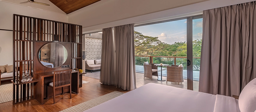 A bright guest room at Jetwing Kandy Gallery reveals expansive views through sliding doors, with a private balcony set above the treetops.