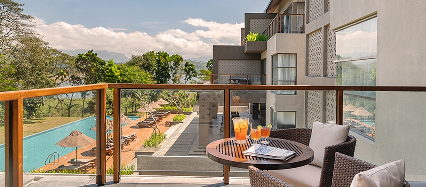 A private balcony at Jetwing Kandy Gallery overlooks the pool and river landscape, framed by crisp mountain horizons and tropical foliage.