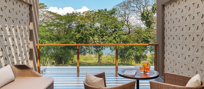 A private balcony at Jetwing Kandy Gallery overlooks lush greenery and the lakeside, with comfortable seating arranged for relaxed outdoor lounging.