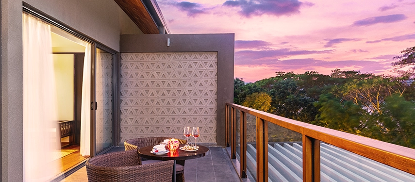 A twilight balcony setting at Jetwing Kandy Gallery is arranged with wine and candles, opening to soft evening colours above the surrounding trees.