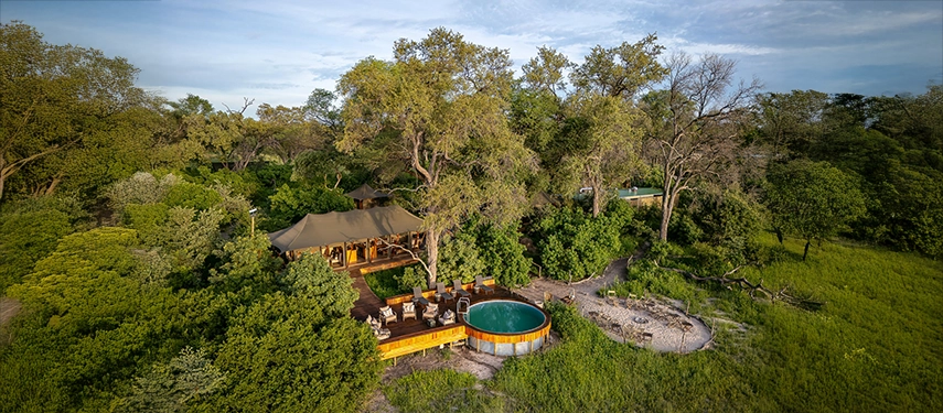 An aerial view reveals Karangoma’s timber decks, pool and tented spaces tucked beneath tall riverine trees on the edge of the floodplain.