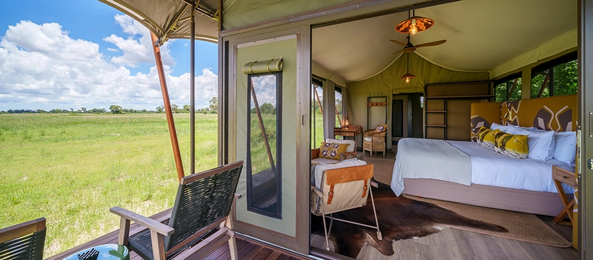 A spacious tented bedroom opens to uninterrupted floodplain views, with soft natural light filling the serene interior.