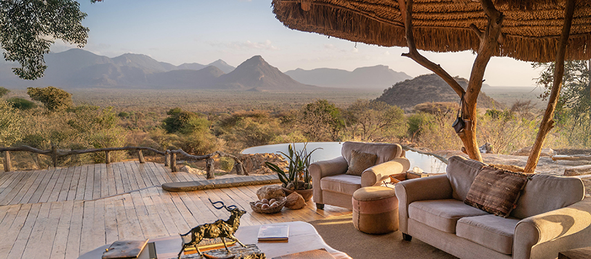 Cosy outdoor seating on a shaded wooden deck at Sarara Camp, overlooking the plains and Mathews Range beyond.