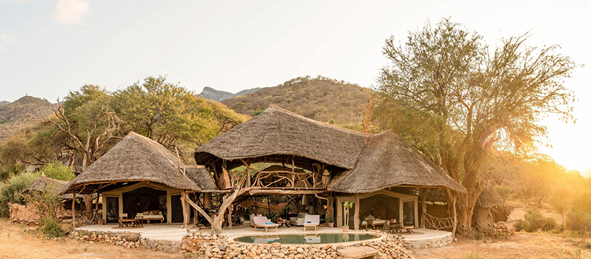 Sarara House at golden hour, with thatched roofs, open-sided rooms, and a private plunge pool nestled in the foothills.