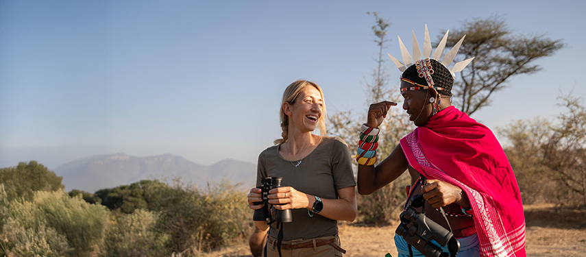 A smiling guest shares a light-hearted moment with a Samburu guide during a nature walk near Sarara Camp.