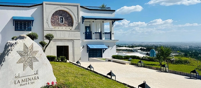 Exterior view of La Menara Hotel & Spa with whitewashed walls, blue balconies, and sweeping views across the valley.
