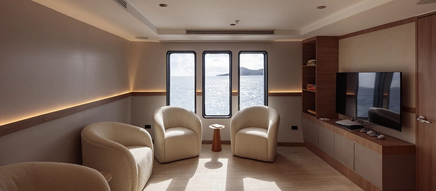Private media room with comfortable seating and large windows aboard the Hermes Galápagos Mega Catamaran.