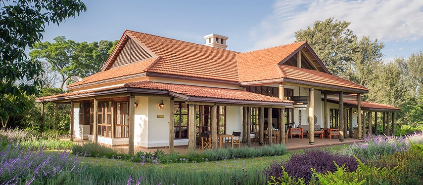 Another exterior perspective of a family cottage at Legendary Lodge in Arusha, surrounded by manicured lawns, lavender borders and mature trees beneath Mount Meru.