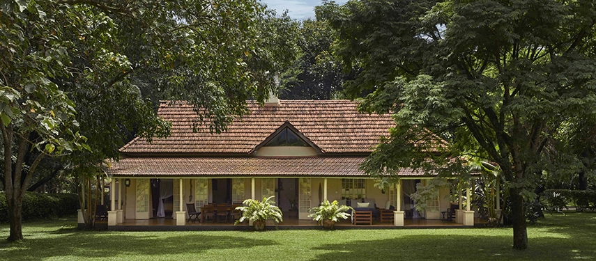 Family cottage exterior at Legendary Lodge in Arusha, framed by lush greenery and shaded verandas, offering a peaceful retreat close to Arusha National Park.
