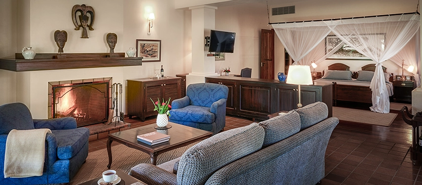 Elegant garden cottage interior at Legendary Lodge in Arusha with soft furnishings, a fireplace and classic décor that blends comfort with East African character.