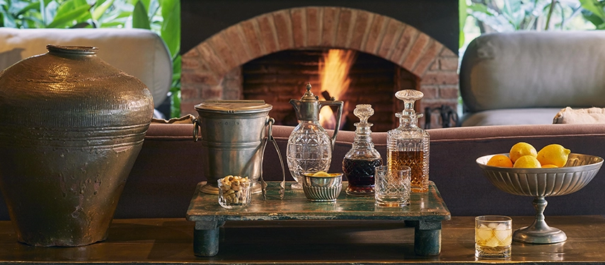 Evening drinks arranged in the main lounge at Legendary Lodge in Arusha, set before a glowing fireplace for relaxed sundowners after a day exploring northern Tanzania.