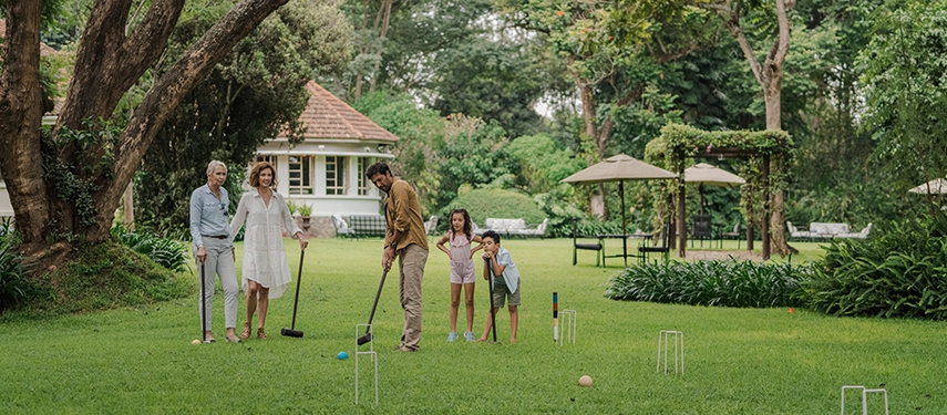Family enjoying garden games on the lawns at Legendary Lodge in Arusha, highlighting relaxed outdoor activities surrounded by lush greenery.