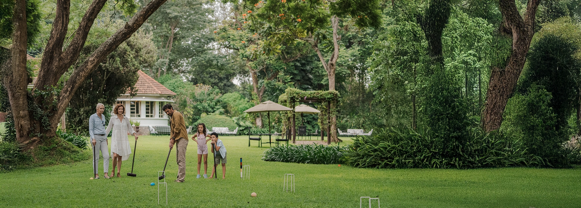 Guests enjoying croquet on the manicured lawns at Legendary Lodge, surrounded by mature trees and tranquil gardens in Arusha.
