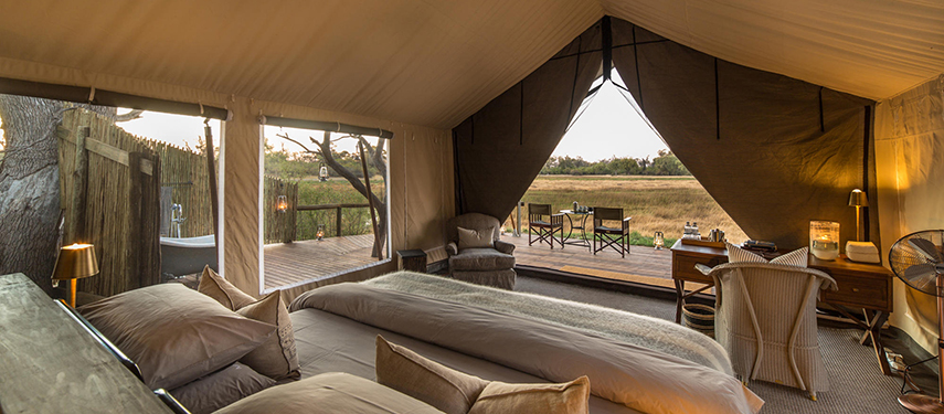 Interior of a luxury tent at Little Machaba showcasing twin beds, elegant furnishings, and views over the bush.