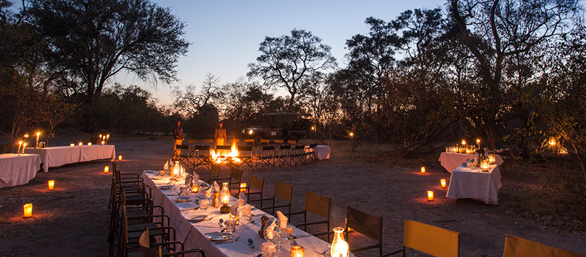 Candlelit bush dinner set up under the stars with long tables and lanterns creating a warm atmosphere in the wilderness.