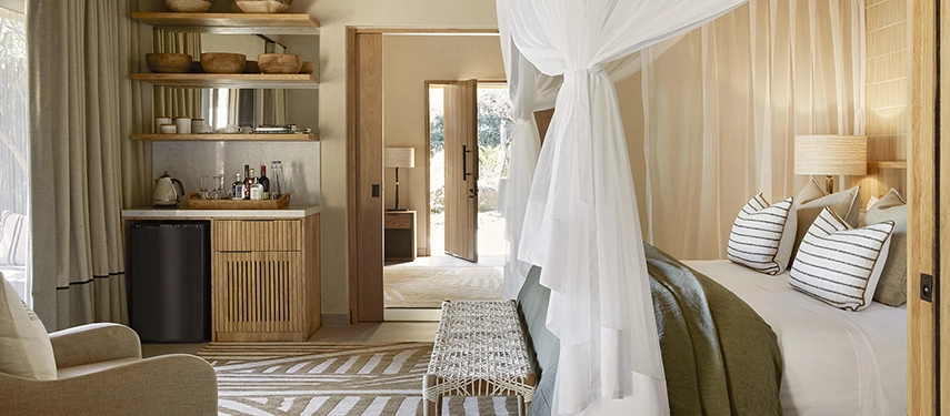 Spacious family suite bedroom at Londolozi Founders Camp with canopy bed, striped cushions, and natural textures.