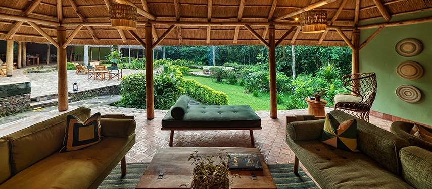 Thatched lounge at Primate Lodge Kibale with rustic seating, woven decor, and views over the landscaped garden.