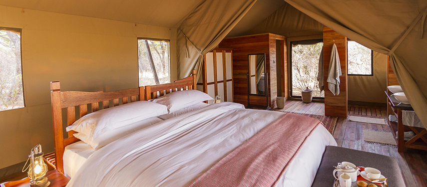 Interior of a luxury tent at Verney’s Camp with a king-size bed, wooden floors and en suite bathroom.