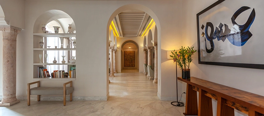Stylish hallway with arched niches, modern artwork, and wooden accents leading into the hotel interior.