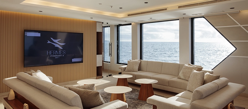 Spacious lounge with modern furnishings and ocean views aboard the Hermes Galápagos Mega Catamaran.