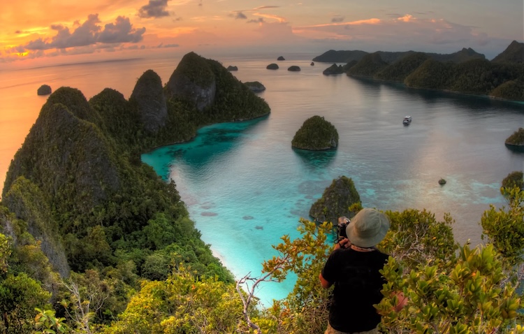 Man on a luxury expedition cruise Overlooks The Raja Ampat Archipelao At Sunset