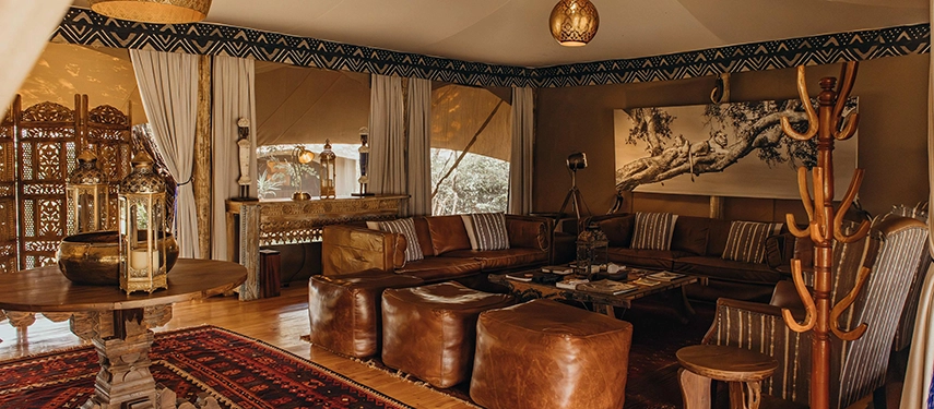 Elegant lounge interiors at Mara Expedition Camp in Kenya, combining leather furnishings, handcrafted décor, and views over the surrounding wilderness.