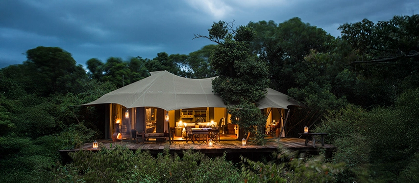 A beautifully lit safari suite at Mara Plains in Kenya, set beneath sweeping canvas and surrounded by riverine forest in the private Olare Motorogi Conservancy.