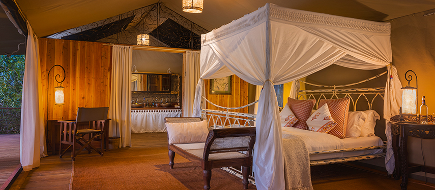 Interior of a spacious tent at Serian ‘The Original’, featuring a four-poster bed, wooden accents, and elegant safari décor.