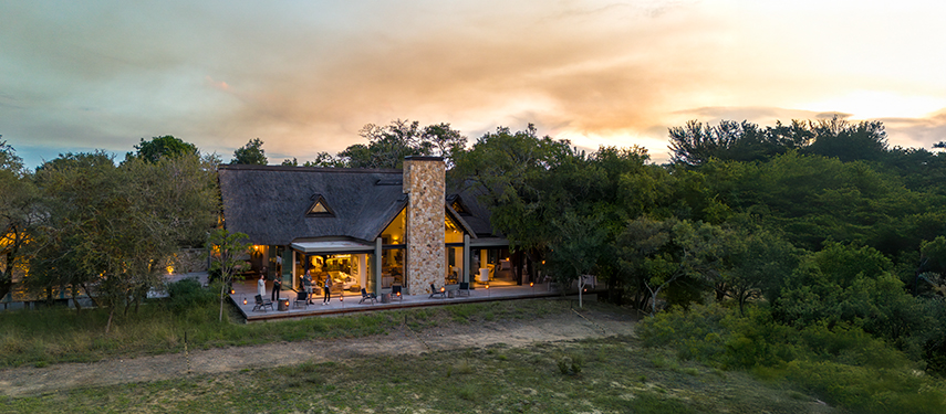 Sunset glow illuminates the main lodge façade and surrounding bushland.