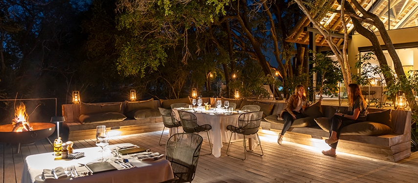 Elegant al fresco dinner setting on the sala deck, softly lit with lanterns and surrounded by nature.
