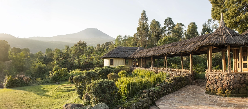 Stone pathways and lush gardens leading to Mount Gahinga Lodge with Mt Gahinga rising in the soft morning light.