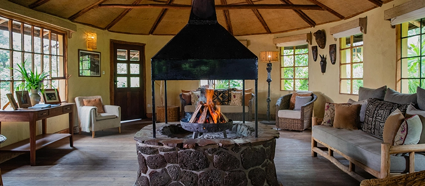 Cosy central lounge at Mount Gahinga Lodge with a suspended central fireplace and handwoven decor.