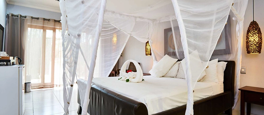Elegant bedroom with white canopy bed and warm lighting at Namutoni