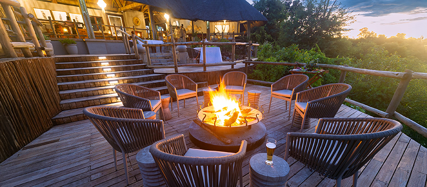 A cosy outdoor firepit lounge area at Ngoma Safari Lodge, perfect for evening relaxation with views over the surrounding forest.