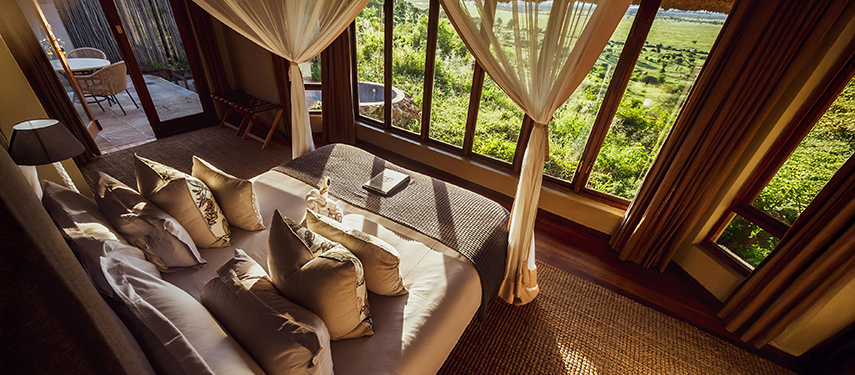 A luxurious suite interior at Ngoma Safari Lodge with large windows offering panoramic views of the Chobe River floodplains.