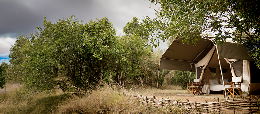 A shaded safari tent with canvas awnings set among bushland at Nkorombo Mobile.