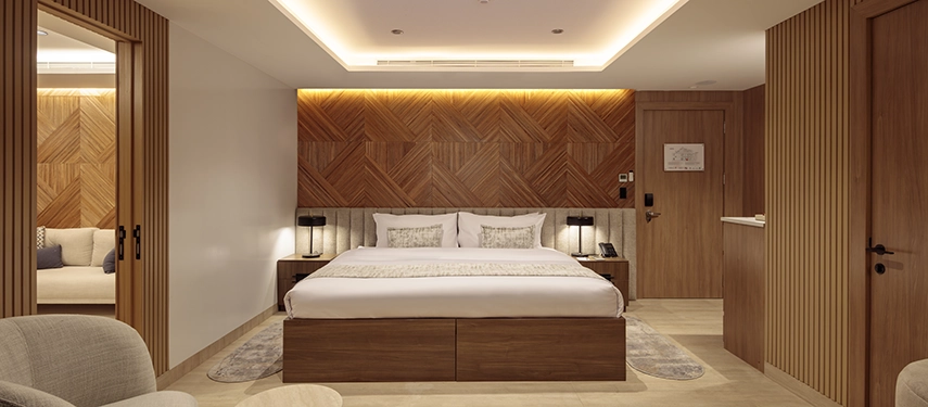 Spacious owner’s suite with warm wood tones and sea-facing windows aboard the Hermes Galápagos Mega Catamaran.