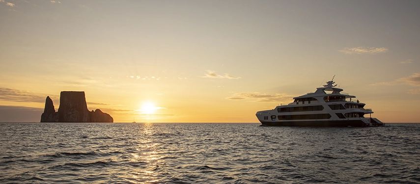 Hermes Galápagos Mega Catamaran anchored off Kicker Rock at sunset.