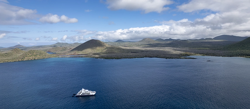 Aerial view of the Hermes Galápagos Mega Catamaran surrounded by volcanic islands.