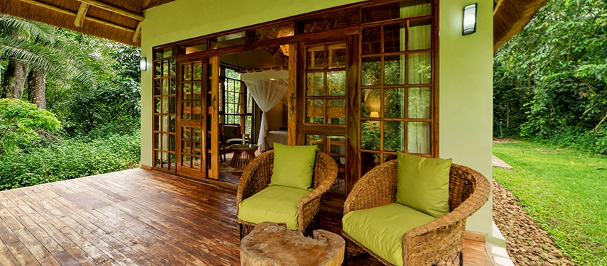 Private terrace at Primate Lodge Kibale with wicker chairs and lush green surroundings.