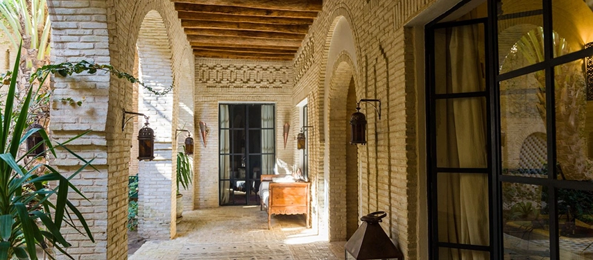 Traditional Tunisian hallway at Dar Tozeur with arched doorways, lanterns, and brick walls.