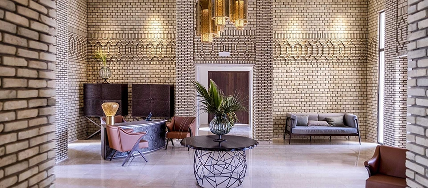 Grand lobby at The Residence Douz with textured brick walls, contemporary chandeliers, and stylish seating.